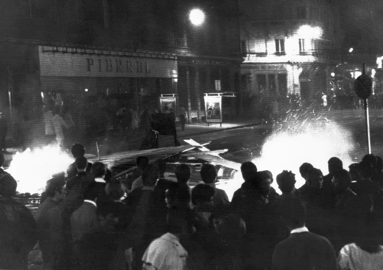 Des manifestants font face aux forces de l'ordre le 27 mai 1968 près du pont La Fayette à Lyon derrière une barricade en feu. • Crédits : AFP PHOTO - AFP