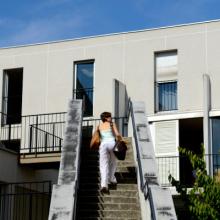 Student with bag going up the stairs to the residence