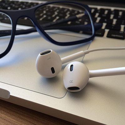 Écouteurs et lunettes posés sur un ordinateur portable